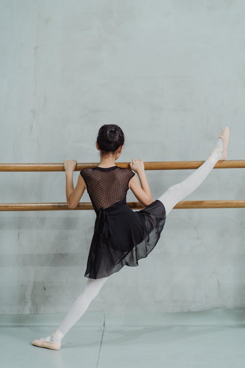 Free Full body back view of faceless flexible girl doing split exercise while rehearsing in ballet studio Stock Photo