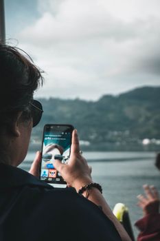 Person capturing scenic Lake Toba view with a smartphone, North Sumatra.
