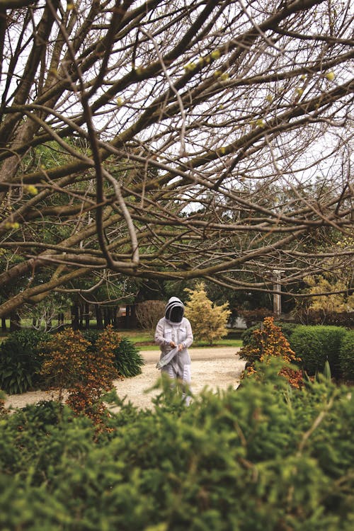 Person in a Protective Workwear Walking Through a Garden