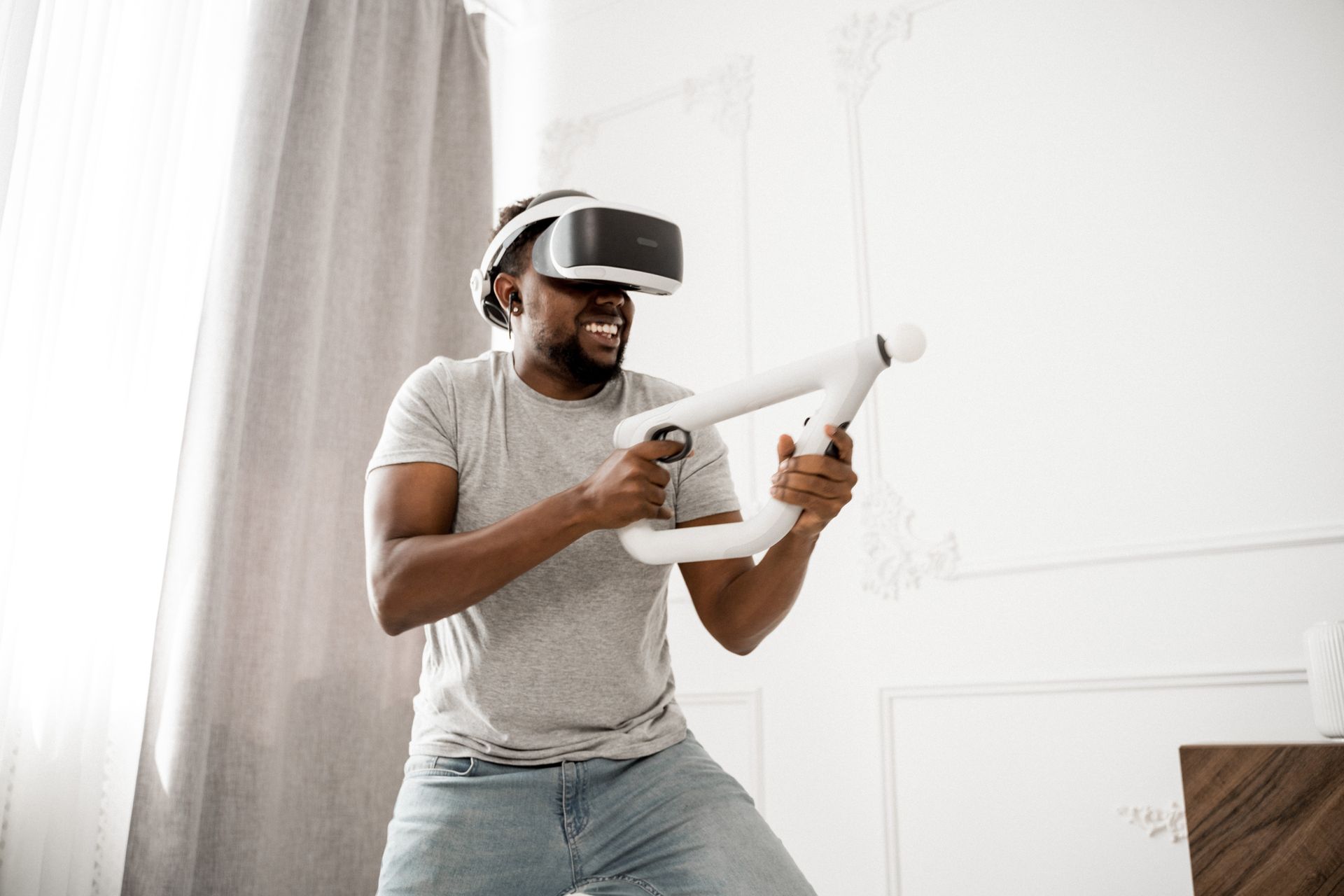 Happy man playing with VR simulator indoors, smiling and engaged in immersive virtual reality experi