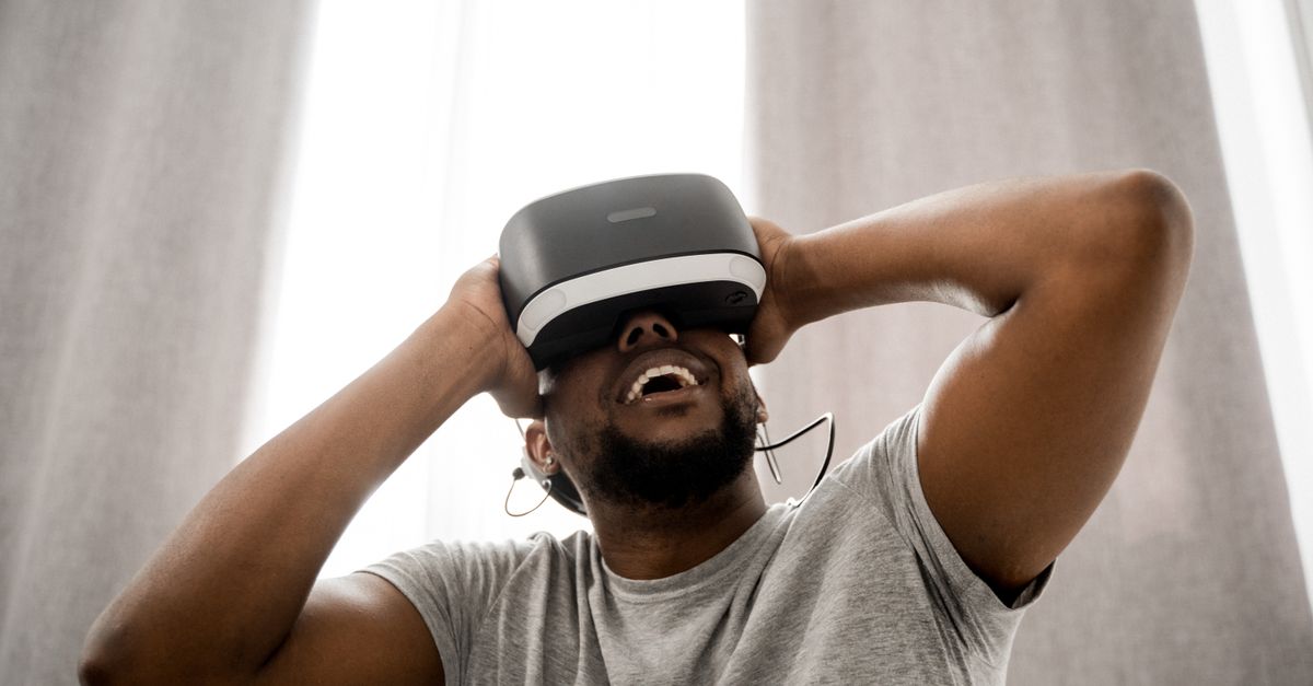 Smiling man with VR headset enjoying a virtual experience indoors, showcasing modern technology.