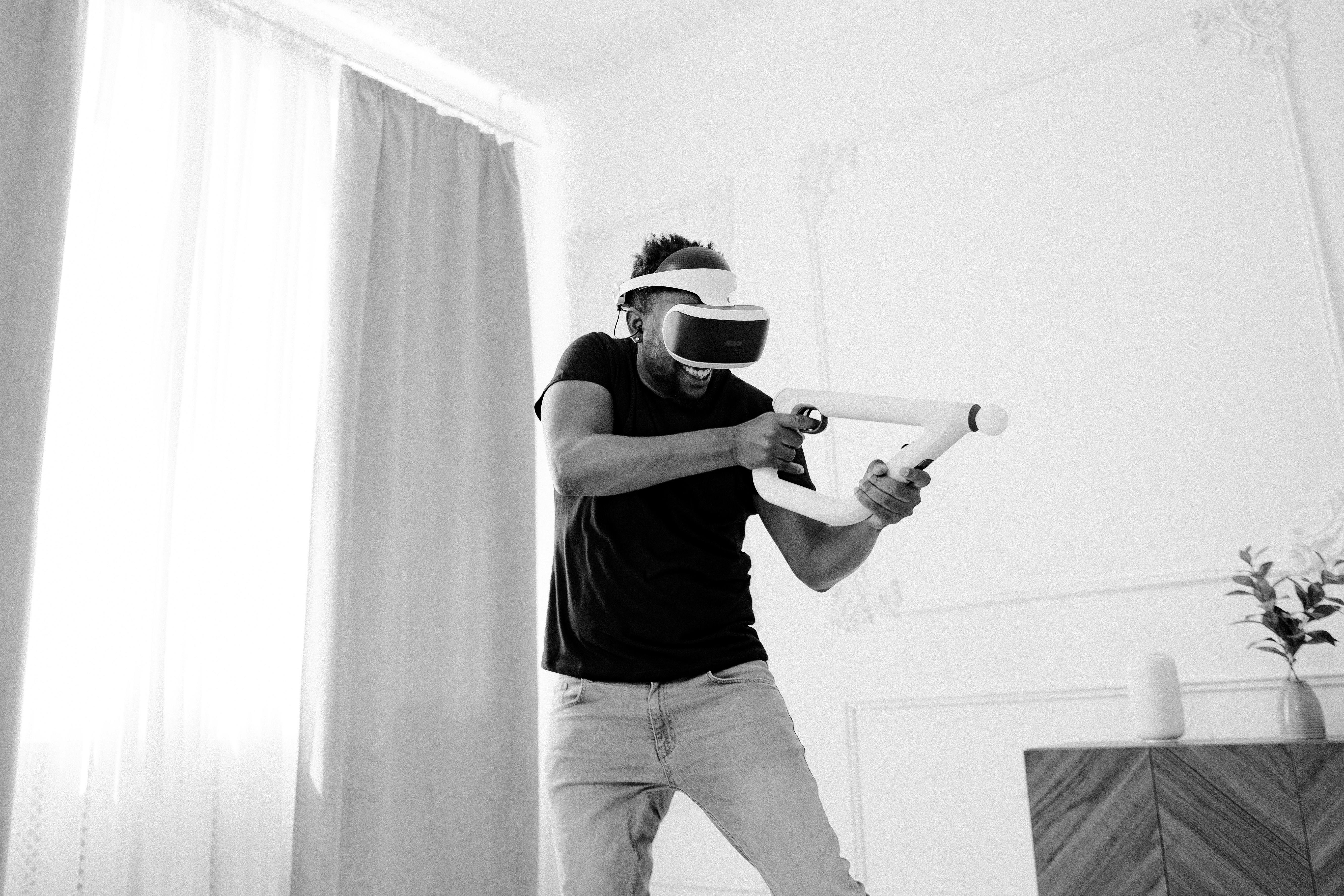 An adult man enjoying VR gaming experience indoors with futuristic virtual reality glasses.