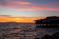 Modern building on water near rocky rough coast and mountains in spectacular sunset