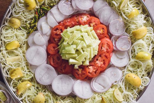 Top view of a vibrant vegetable salad platter with fresh cucumbers, tomatoes, onions, and lemons.
