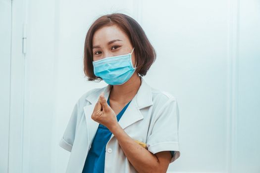 A female doctor in a medical uniform wearing a face mask, indoors setting.
