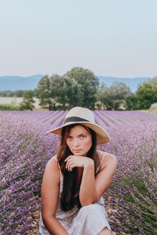 Woman in hat leaning on hand in lavender field