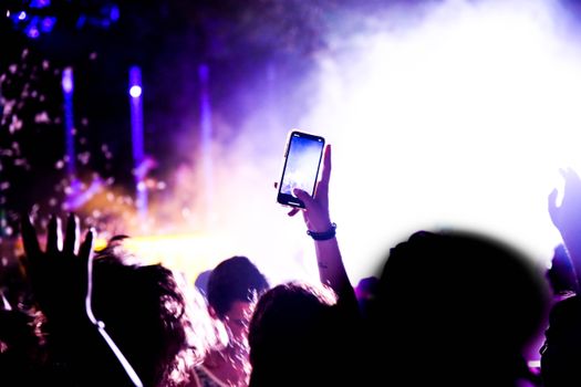 Vibrant concert scene with a crowd capturing the performance on smartphones.