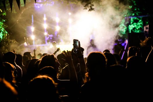 Dynamic crowd enjoying a lively outdoor concert with colorful lights and vibrant atmosphere.