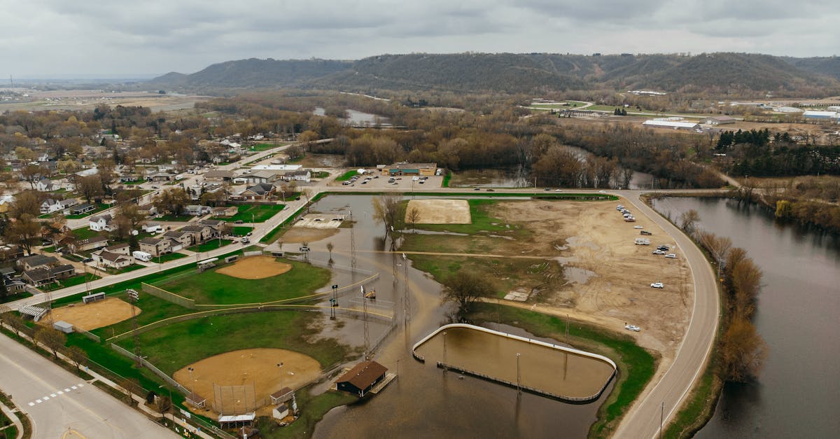 Photo by Chris Flaten Aerial view of a flooded park area with baseball fields and roads during an overcast day.