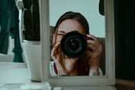 Woman taking photo through small mirror