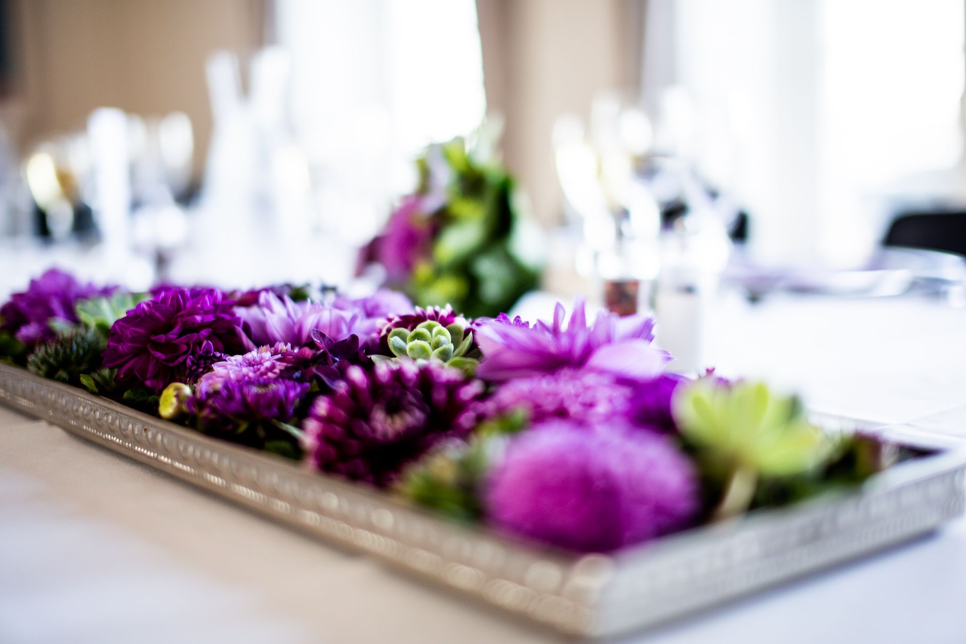 Vibrant purple flowers arranged in a modern centerpiece on a decorated table.