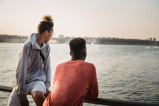 Young multiracial male friends in casual clothes standing on city waterfront and having conversation in early evening