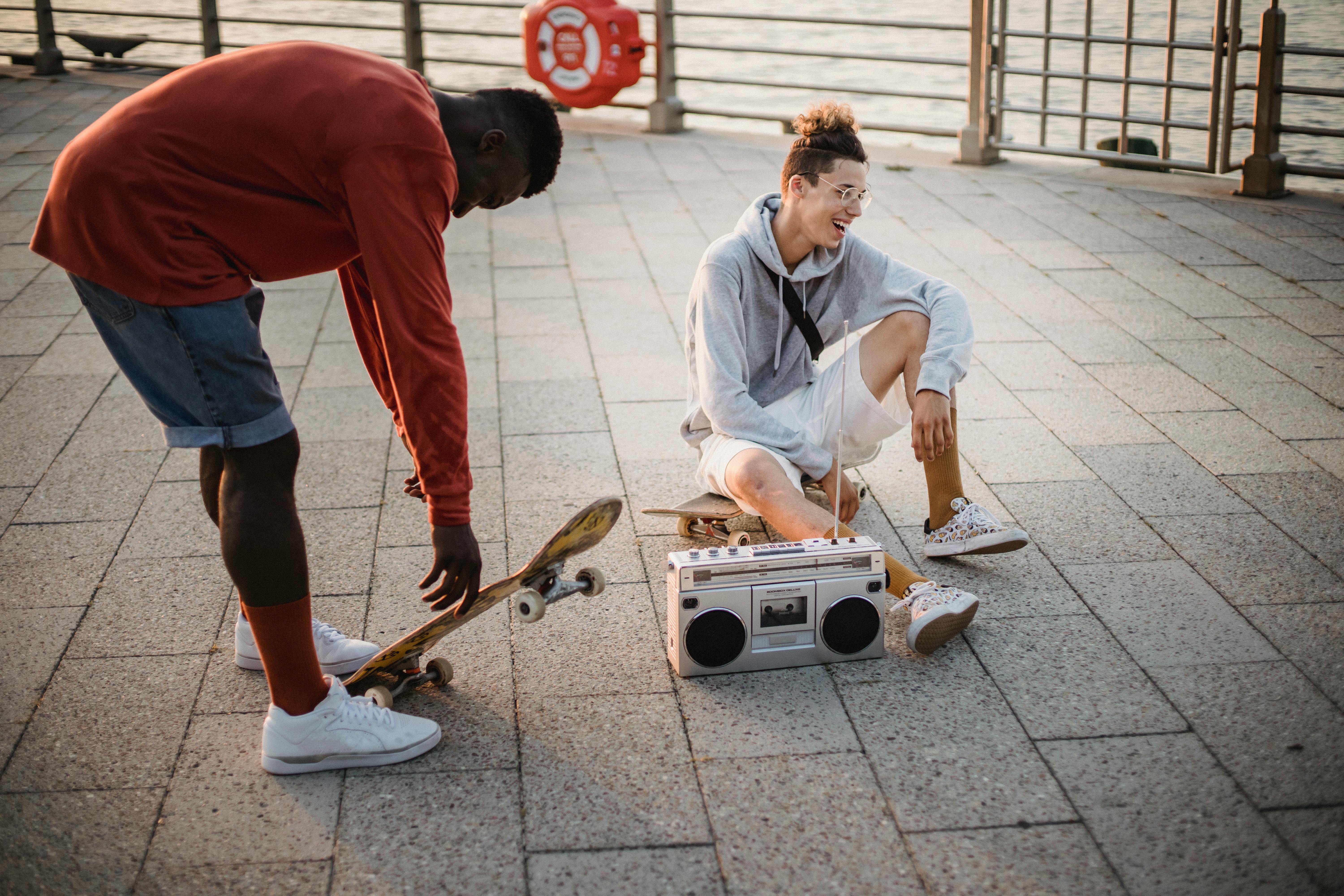 cheerful multiethnic male skaters listening to music via boombox