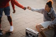 两个朋友一边享受音乐和户外滑板，一边碰拳分享喜悦
