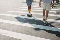 一名匿名黑人朋友在过马路时骑滑板的后视图