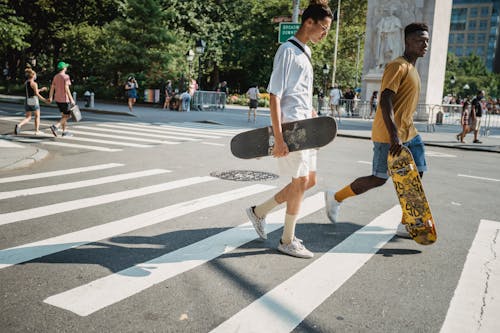 Diverse friends with skateboards crossing road