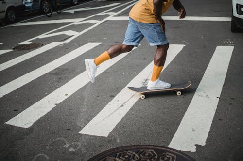 Black man riding skateboard on pedestrian crossing