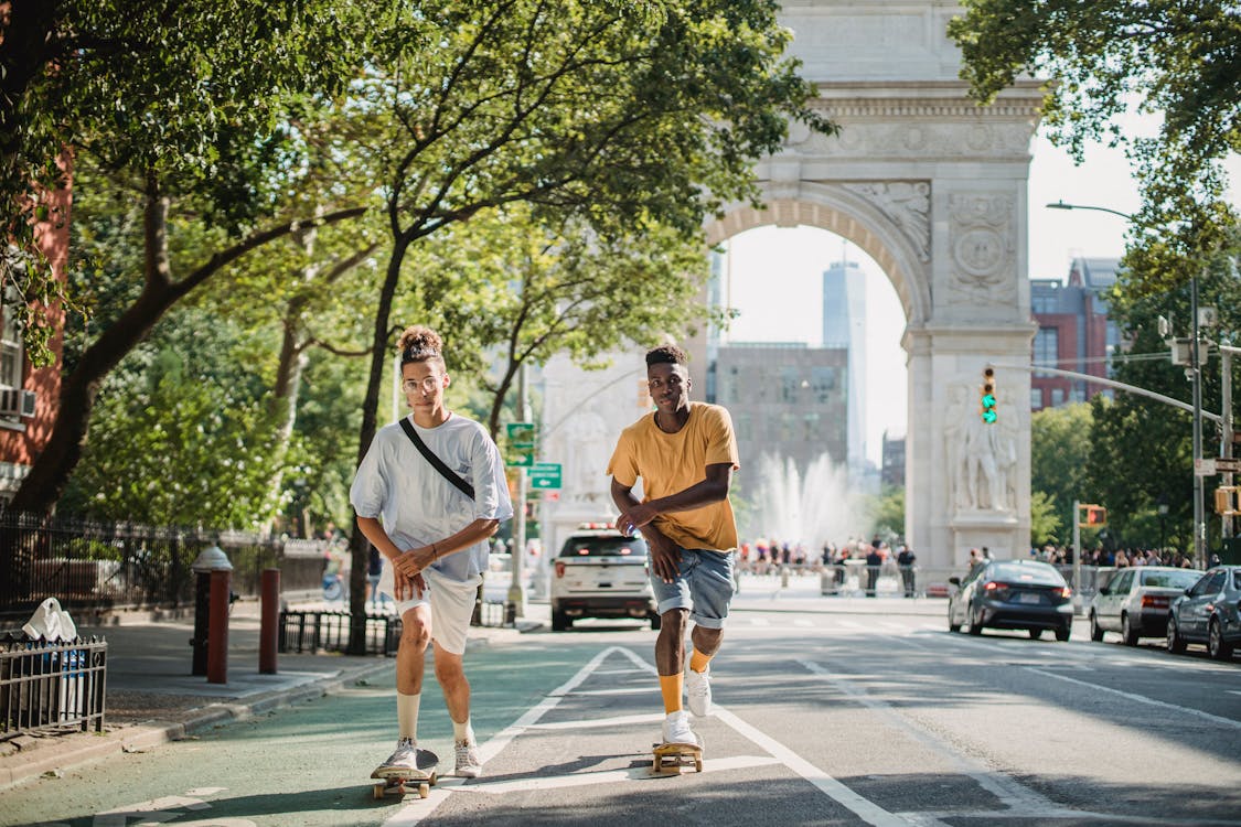 Active diverse friends riding skateboard on city street · Free Stock Photo
