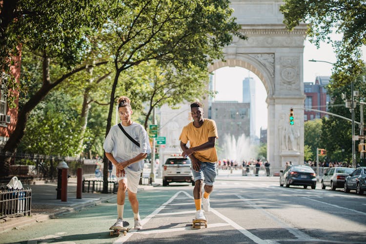 Active Diverse Friends Riding Skateboard On City Street