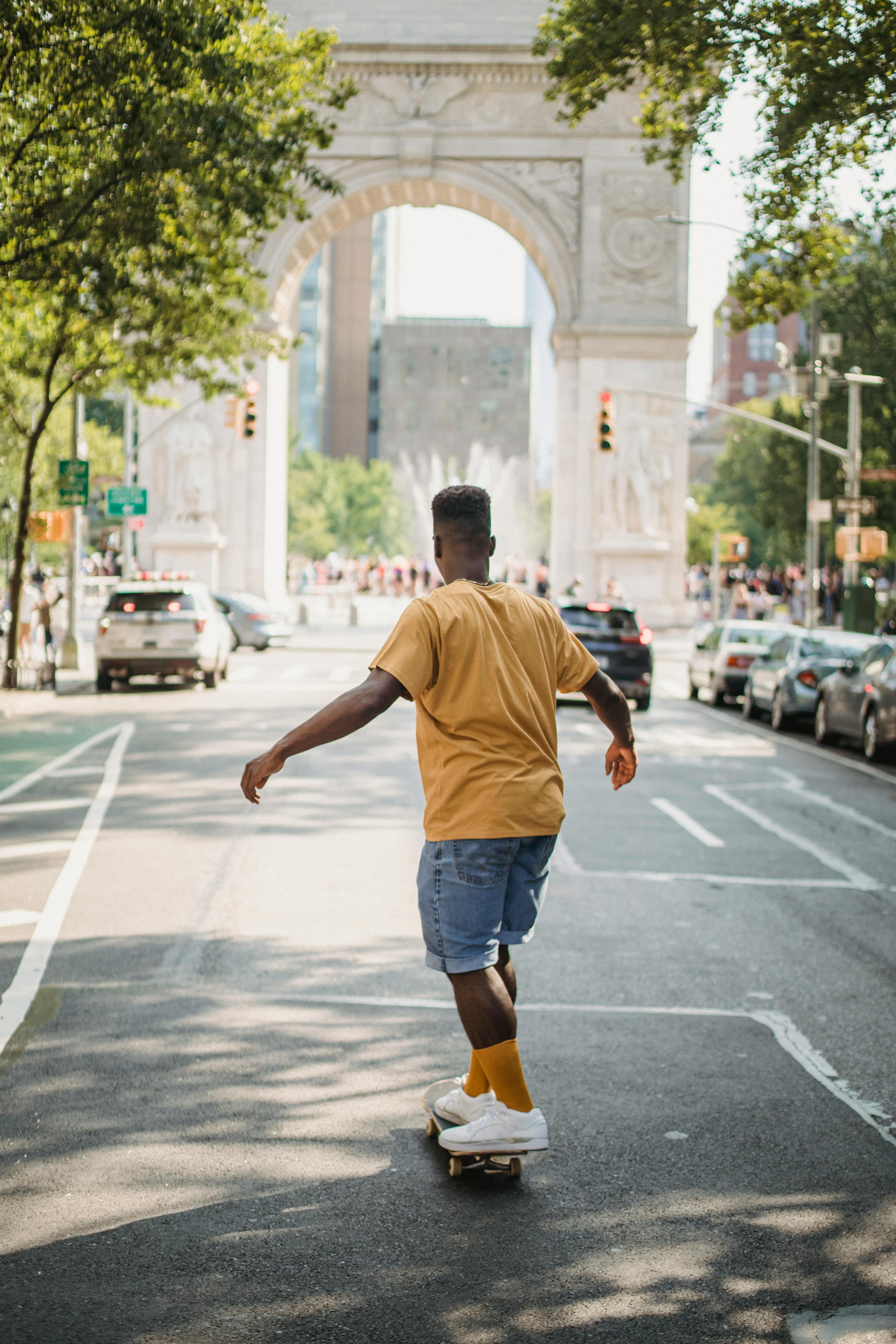 black man riding skateboard on road