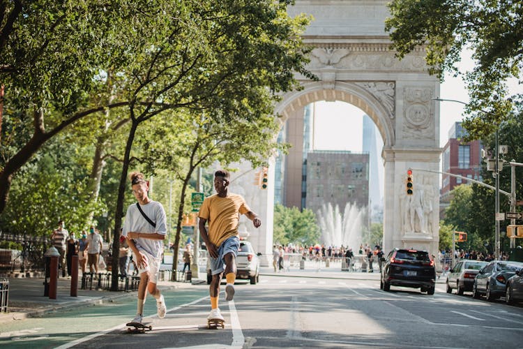 Trendy Diverse Male Teens Skateboarding On City Street In Sunlight