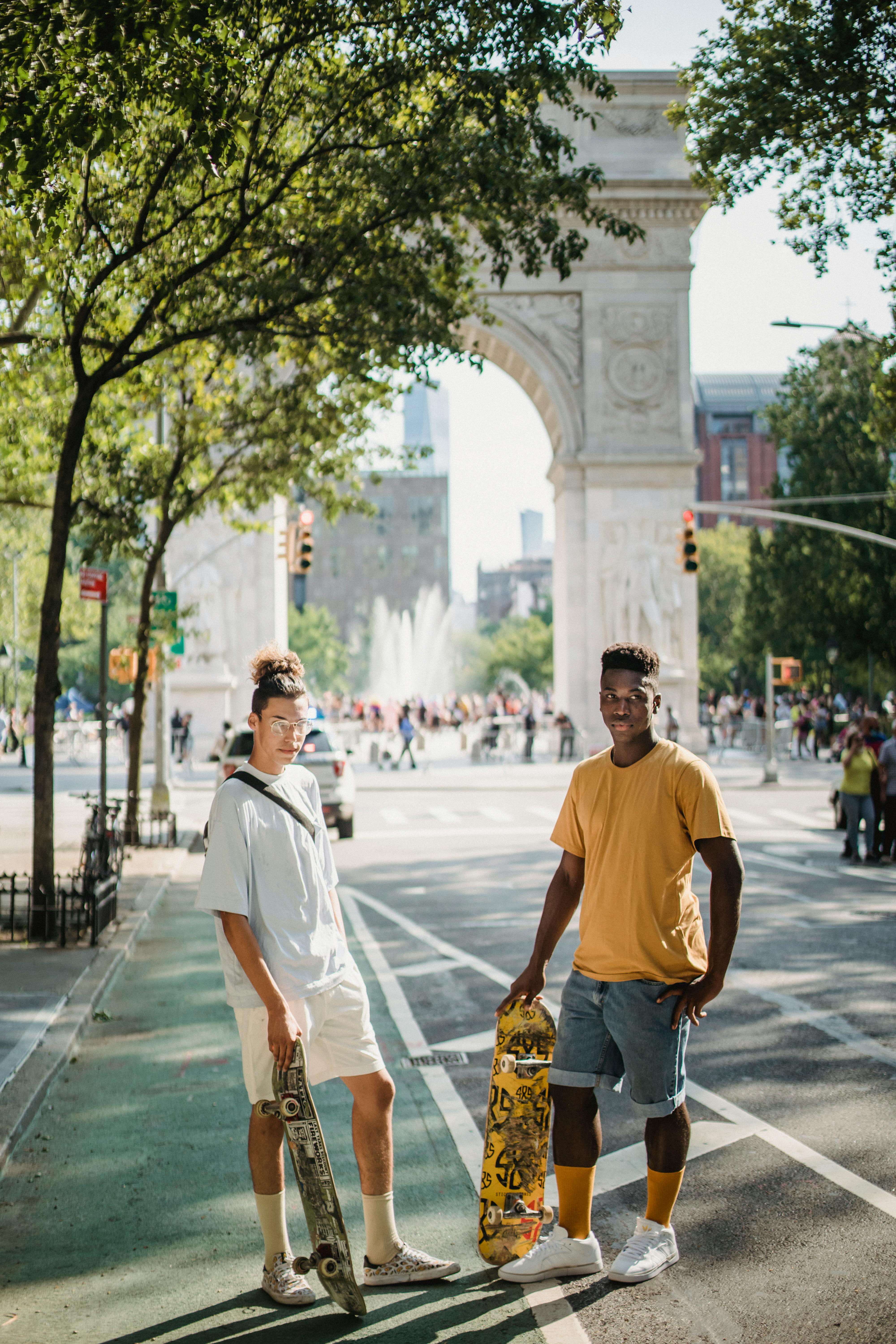 fit young diverse male friends standing on street near triumphal arch on sunny day