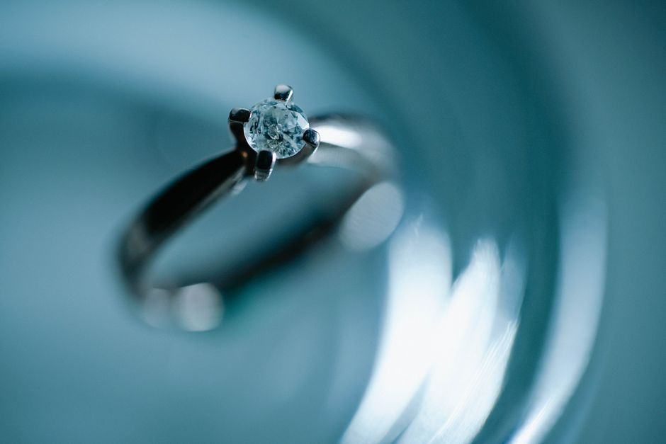 きらめく青い表面のダイヤモンド婚約指輪のクローズアップで、エレガンスとロマンスを呼び起こします。