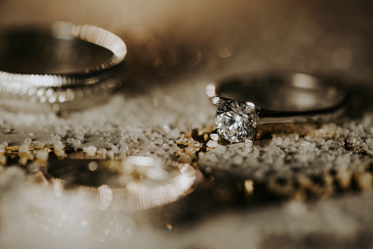 Anillo solitario de oro con diamante sobre arena dorada