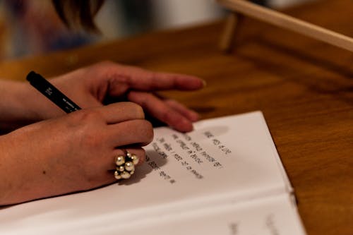 Close-up of Woman Writing in a Notebook 