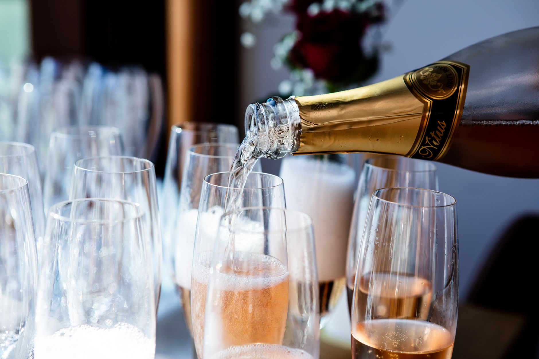 A hand holding a glass of sparkling wine against a bright background