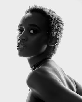 Black and white of African American female with short curly hair and naked shoulders looking at camera