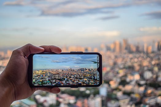 Close-up of a smartphone capturing a vibrant cityscape from an urban rooftop view.