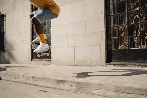 урожай афро американский спортивный мужчина прыгает на скейтборде в солнечном свете