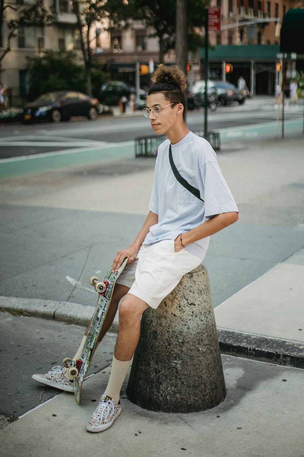 Positive ethnic male skater sitting on street bollard · Free Stock Photo