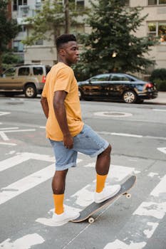 Young man confidently skating across a city street crosswalk in a vibrant urban setting.