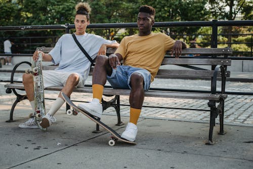 Free Serious friends with skateboards resting on bench Stock Photo
