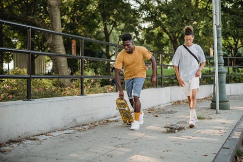 Free Diverse skaters riding on street along park Stock Photo