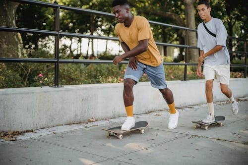 Free Diverse male friends riding skateboards together in city Stock Photo