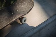 Shabby black skateboard nose on concrete surface in sunlight