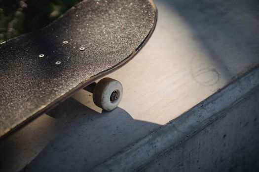 Shabby black skateboard nose on concrete surface in sunlight