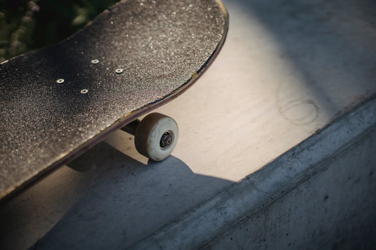 Shabby Black Skateboard Nose On Concrete Surface In Sunlight