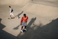From above of man diverse friends accelerating for performing extreme stunt on skateboard during training on modern ramp in skate park