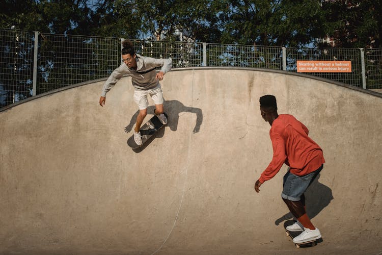 Active Diverse Skateboarders Performing Tricks In Skate Park