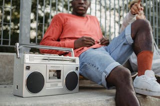 Diverse friends chilling on street with vintage radio cassette recorder