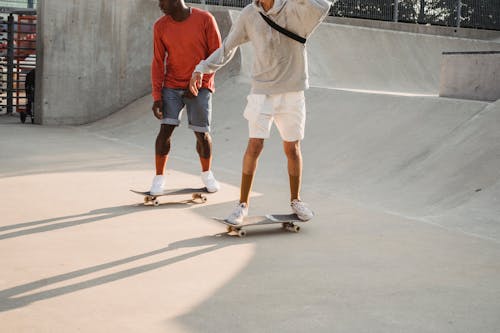 Free Young friends learning how to ride skateboard on ramp in skate park Stock Photo