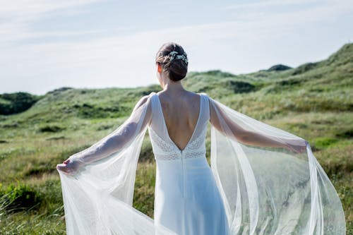 Free Woman in White Wedding Dress Standing on Green Grass Field Stock Photo