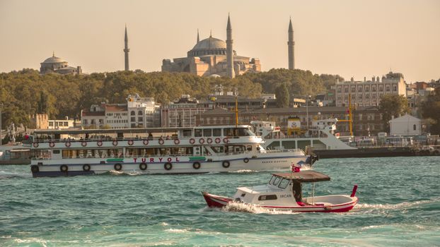 Scenic view of boats on the Bosphorus with Hagia Sophia in Istanbul at sunset.