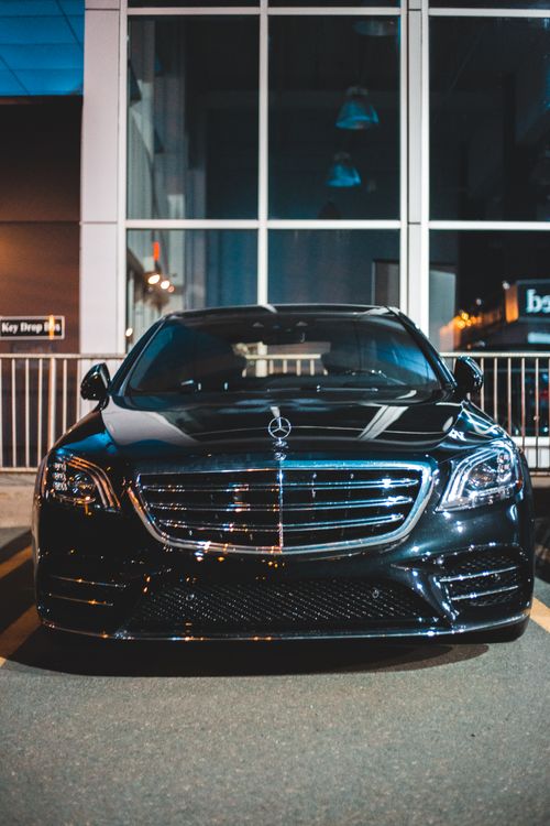 Free Black luxury car with glossy surface and tuned body kit on parking next to tall construction Stock Photo