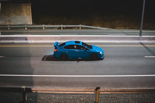 A sleek blue car driving on an empty highway at night, exuding speed and freedom.
