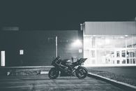 Black and white of stylish motorcycle parked on asphalt surface on local street of city at night
